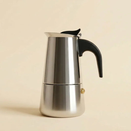 Cafetière italienne 9 tasses en inox, poignée noire, sur fond crème