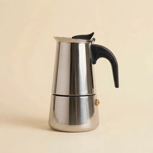 Cafetière italienne induction 4 tasses en inox, poignée noire, sur fond crème